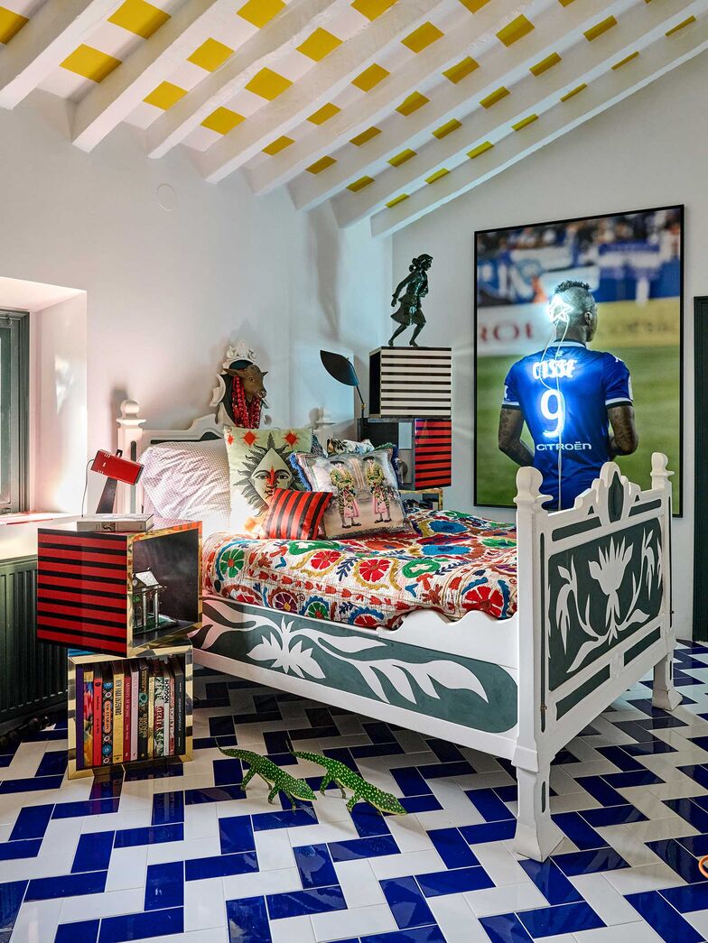 Trouvé dans la maison, le lit a été peint et décoré par Sacha Walckhoff et Octavi Hernandez Farre. Suzani ancien, WOWO. Coussins, dont « Le Torrero » d’après carte postale chinée dans la région, Christian Lacroix Maison. Cubes sérigraphiés de Sacha Walckhoff, Christian Lacroix Maison × Roche Bobois. Lampe vintage L’AGRAFÉE DOUBLE ROTULE de Serge Mouille (1958). Phototographie « La Tonsure », de Non Futbol Club, Galerie Alain Gutharc.