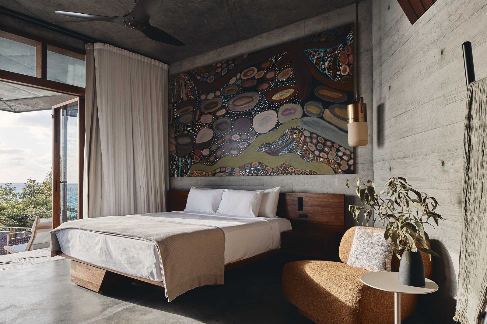 Dans la chambre à coucher, le lit en palissandre de Nouvelle-Guinée a été conçu sur mesure par JDA Co. Fauteuil GOGAN de Patricia Urquiola, Moroso. Suspension Paul Morris. Au mur, une œuvre de l’artiste aborigène Susie Pascoe.